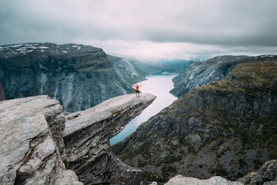 person standing on gray high-rise rock formation at daytime