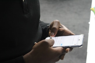 Close-up of hands typing comments on a smartphone with a warm background.