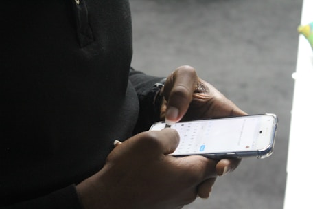 Close-up of hands typing on a smartphone showing a business form submission screen.