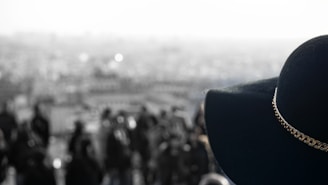 Evening city skyline blurred in the background with a Lumina Apparel cap in sharp focus in the foreground.