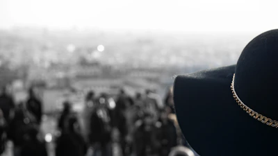Close-up of a black and orange ‘comeback city’ hat resting on a concrete ledge with city skyline blurred behind.