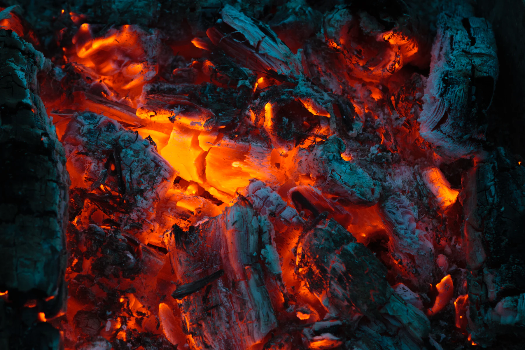 Close-up of a bed of wood coals glowing bright orange under a crust of grey and white ash