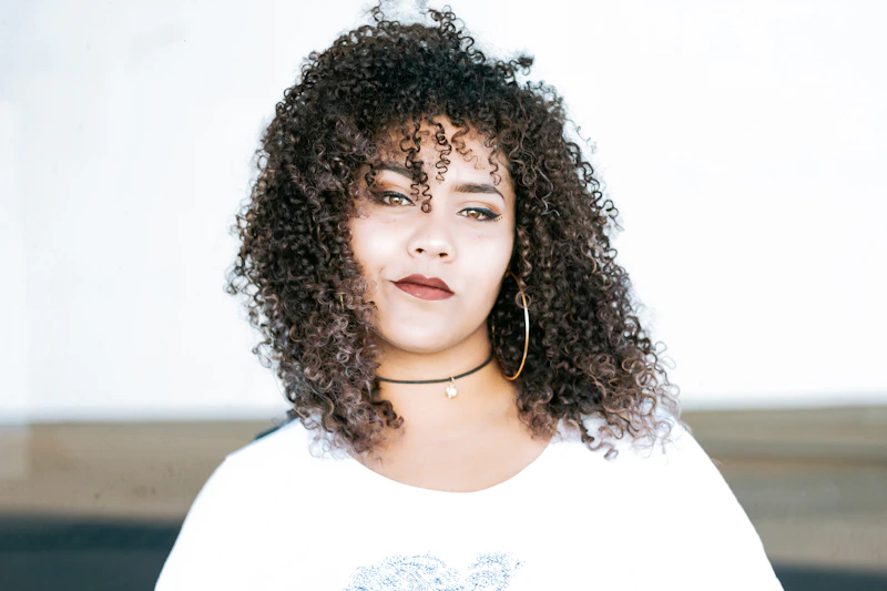 curvy woman in white scoop neck top by wall
