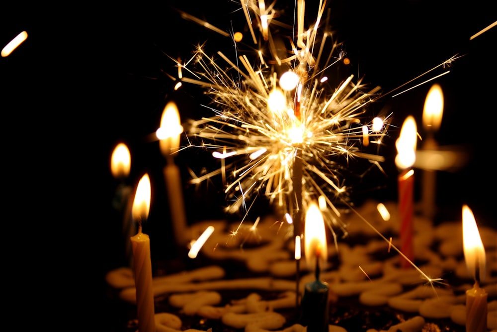 close up photography of sparkler beside candles