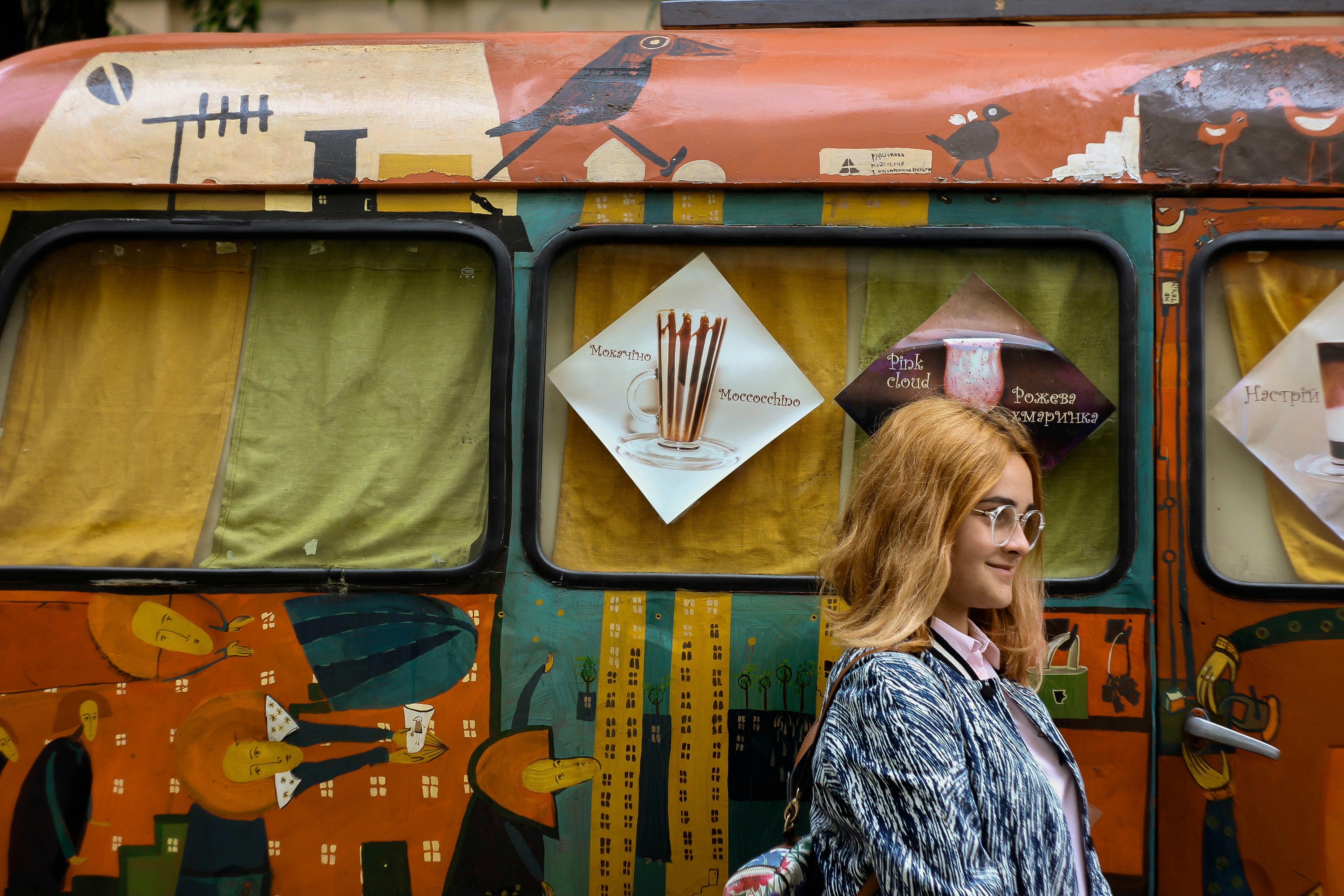 woman in gray shirt standing beside vehicle, Woman with decorated bus