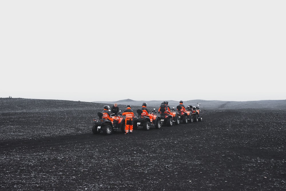 Gruppe von Menschen in orangefarbenen Anzügen, die ein ATV fahren