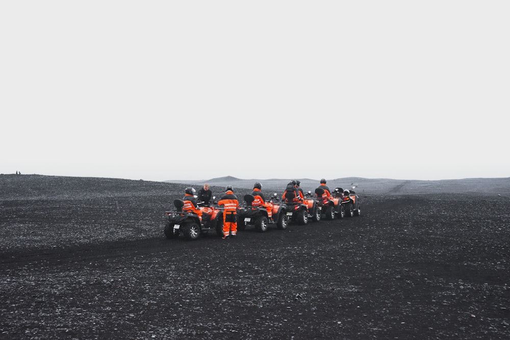 group of people in orange suit riding a ATV