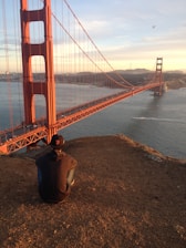 man in brown hoodie jacket staring at Golden Gate bridge