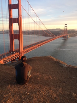 man in brown hoodie jacket staring at Golden Gate bridge
