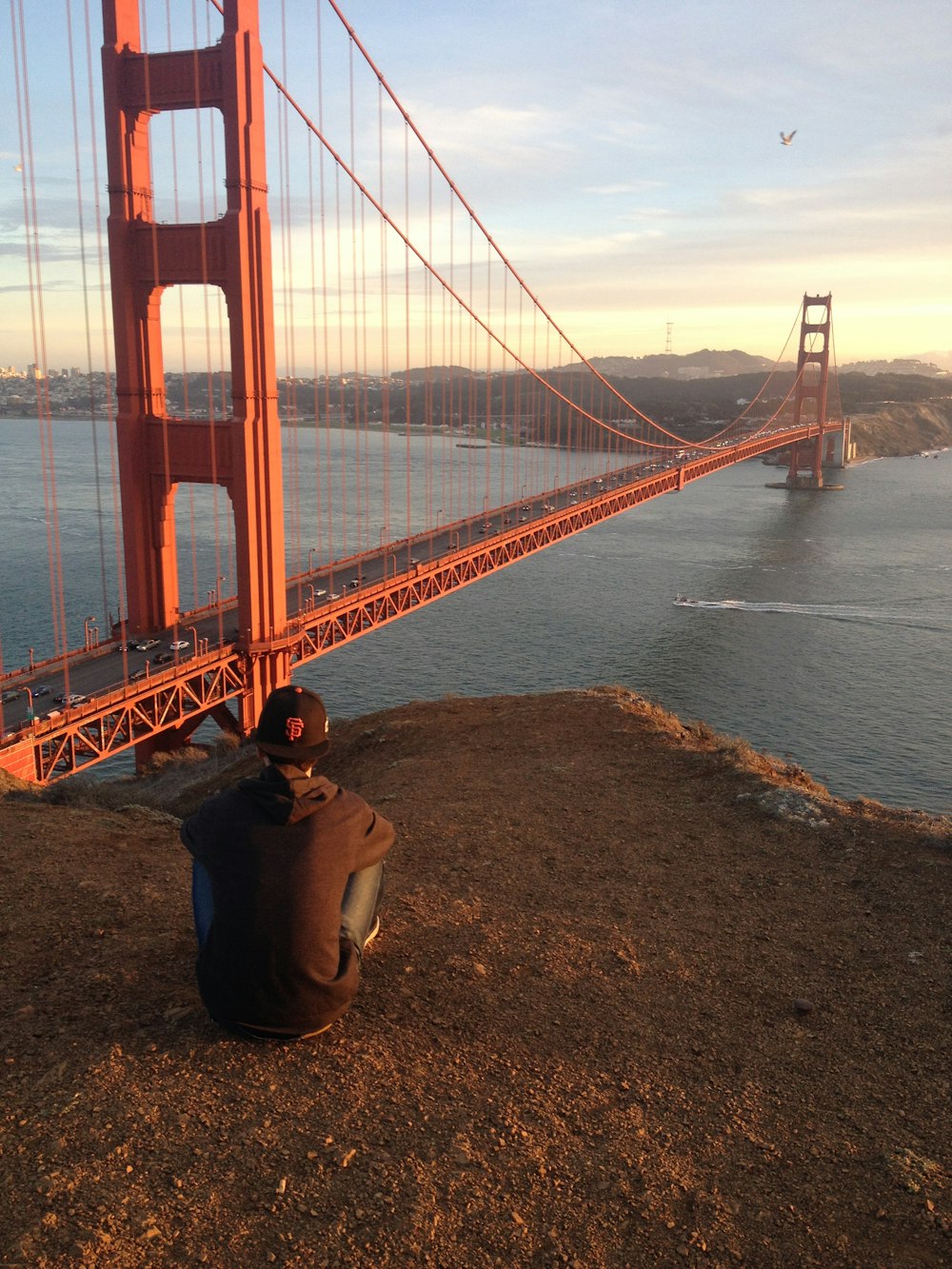 man in brown hoodie jacket staring at Golden Gate bridge