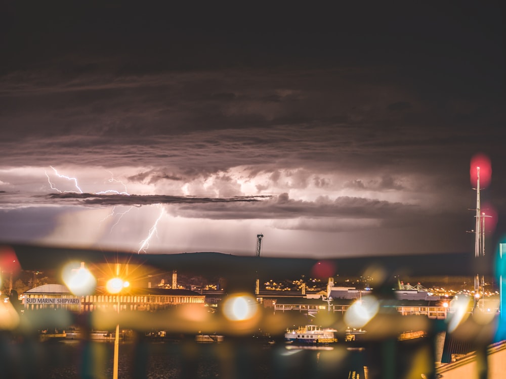 high angle photography of buildings under gray sky with lighting strikes