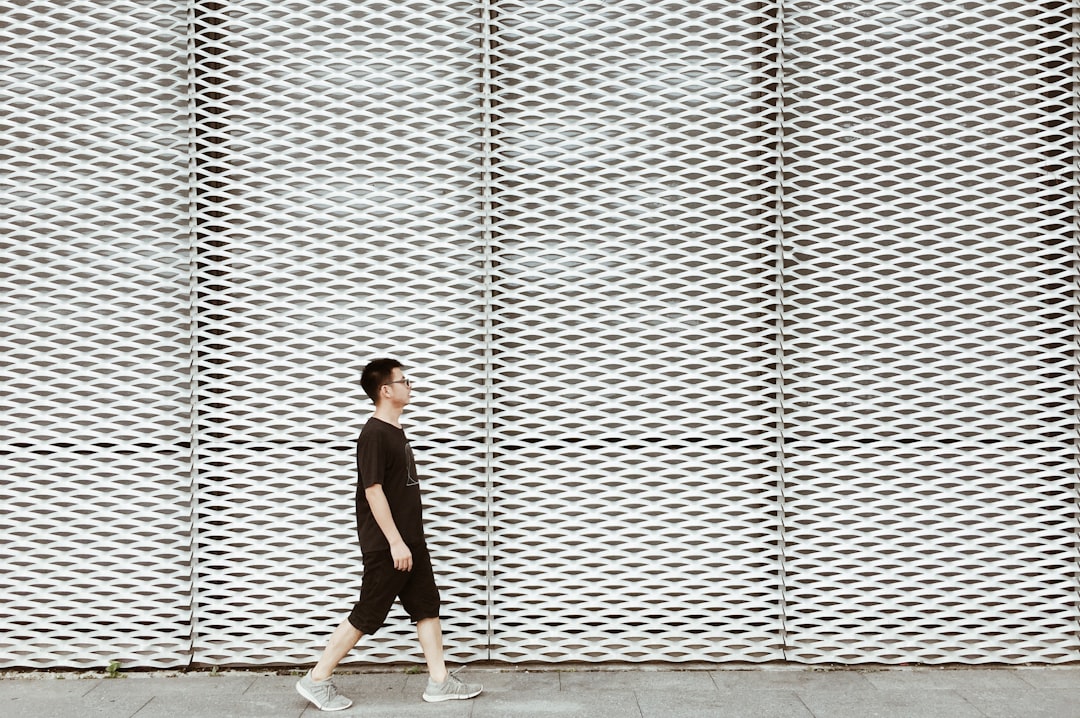 man in black tank top and white shorts walking on sidewalk