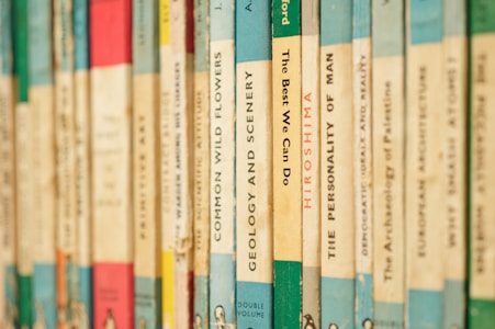 A close-up of a row of vintage paperback books with various titles on their spines. The books are arranged vertically, showing a variety of colors and fonts, giving a nostalgic and scholarly atmosphere.