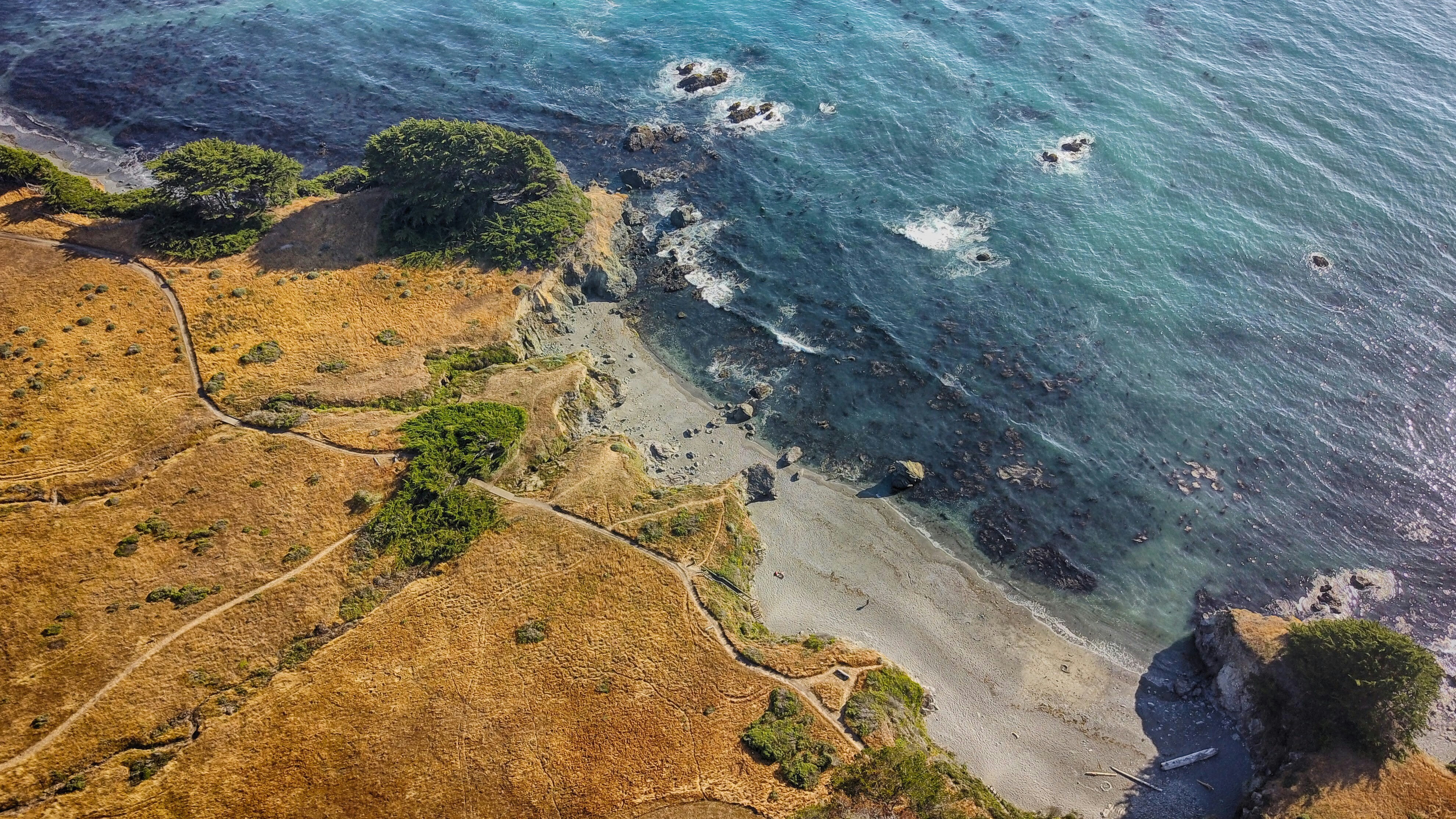 high-angle photography of brown mountain beside body of water at daytime