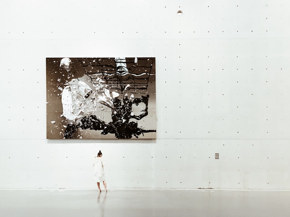 Uma mulher em pé perto de uma pintura em uma galeria de arte moderna