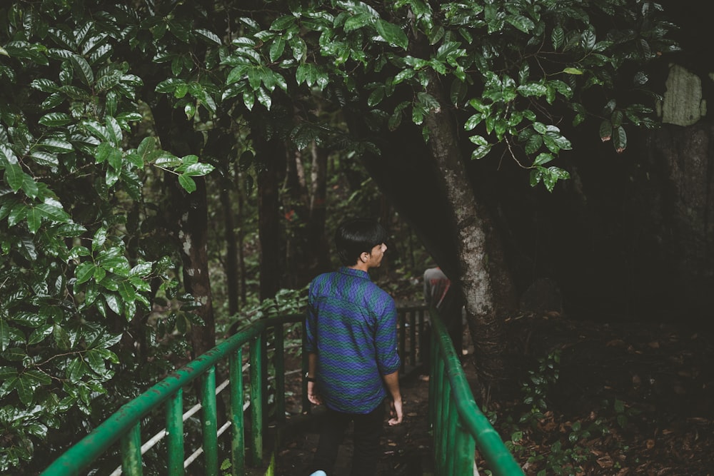 man in blue dress shirt walking under tree