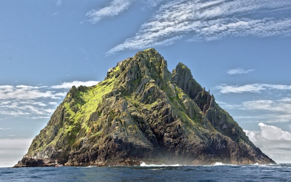 a jagged, mountainous island in the middle of a blue sea