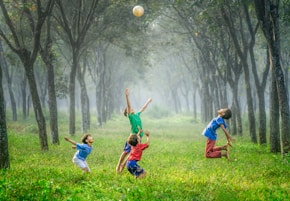 four boy playing ball on green grass