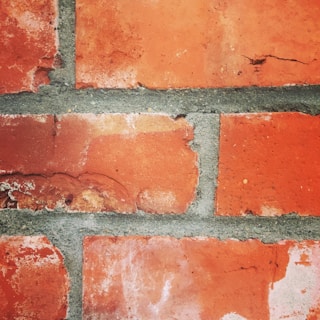 Hands carefully repointing weathered brick mortar on an old wall.