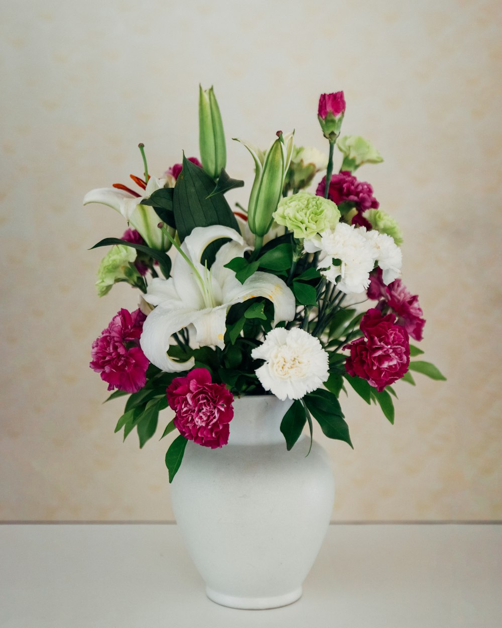 白い花瓶に白と紫の花びらのフラワーアレンジメント