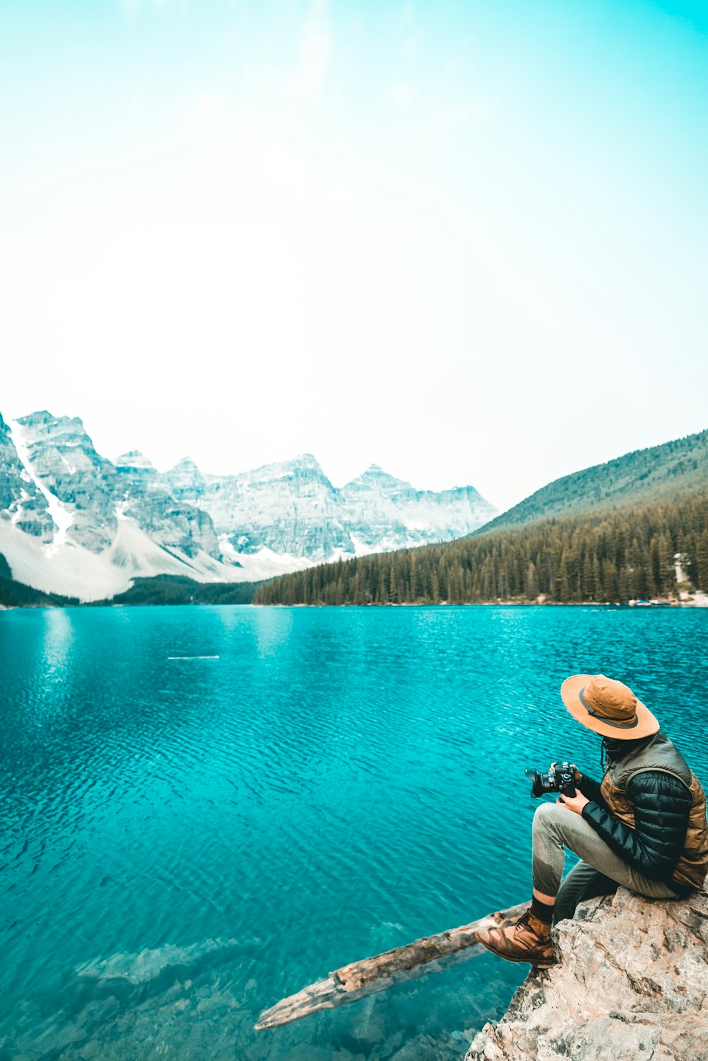 person sitting on cliff near body of water