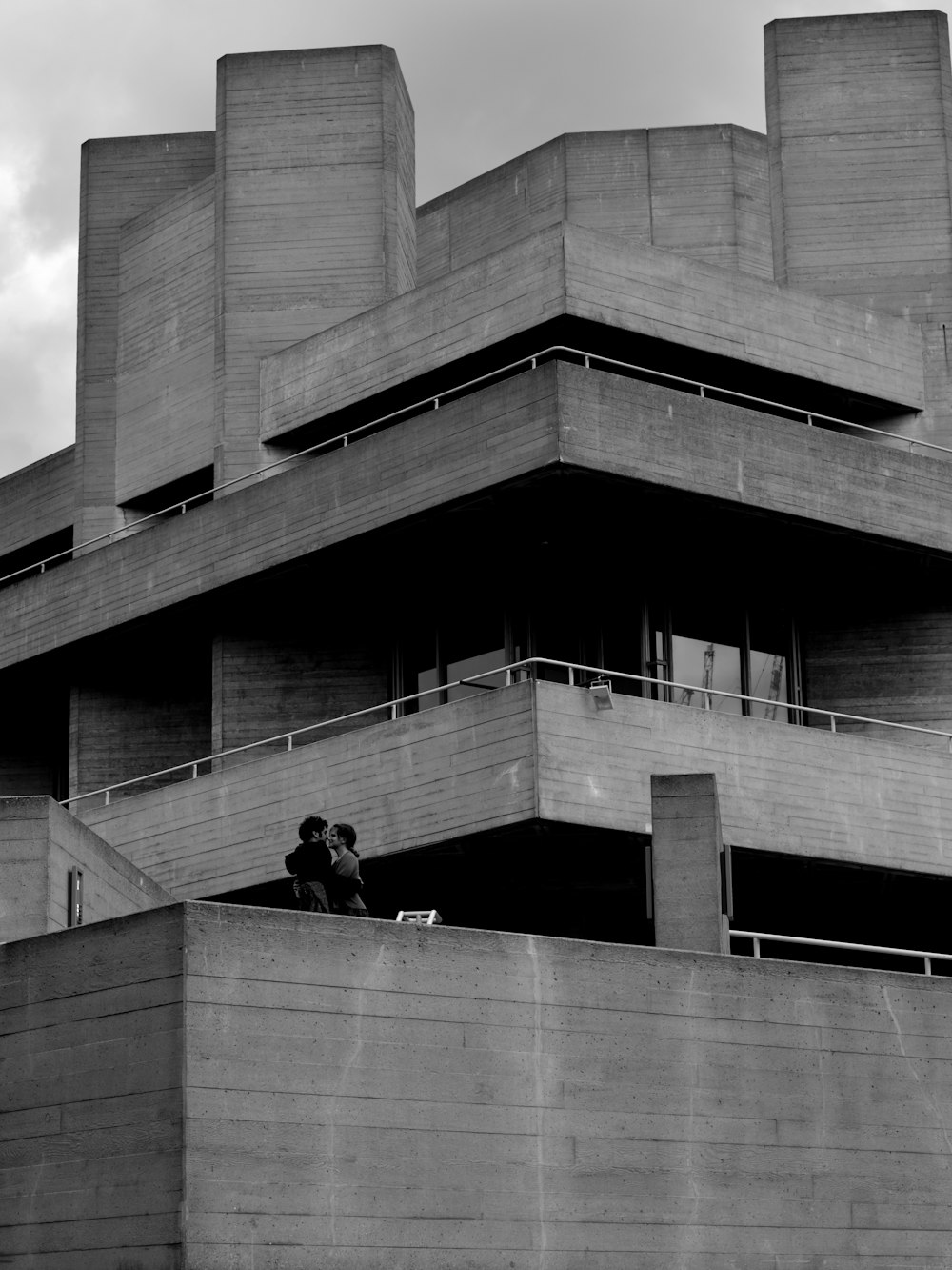 grayscale photography of two couple kissing on top of building