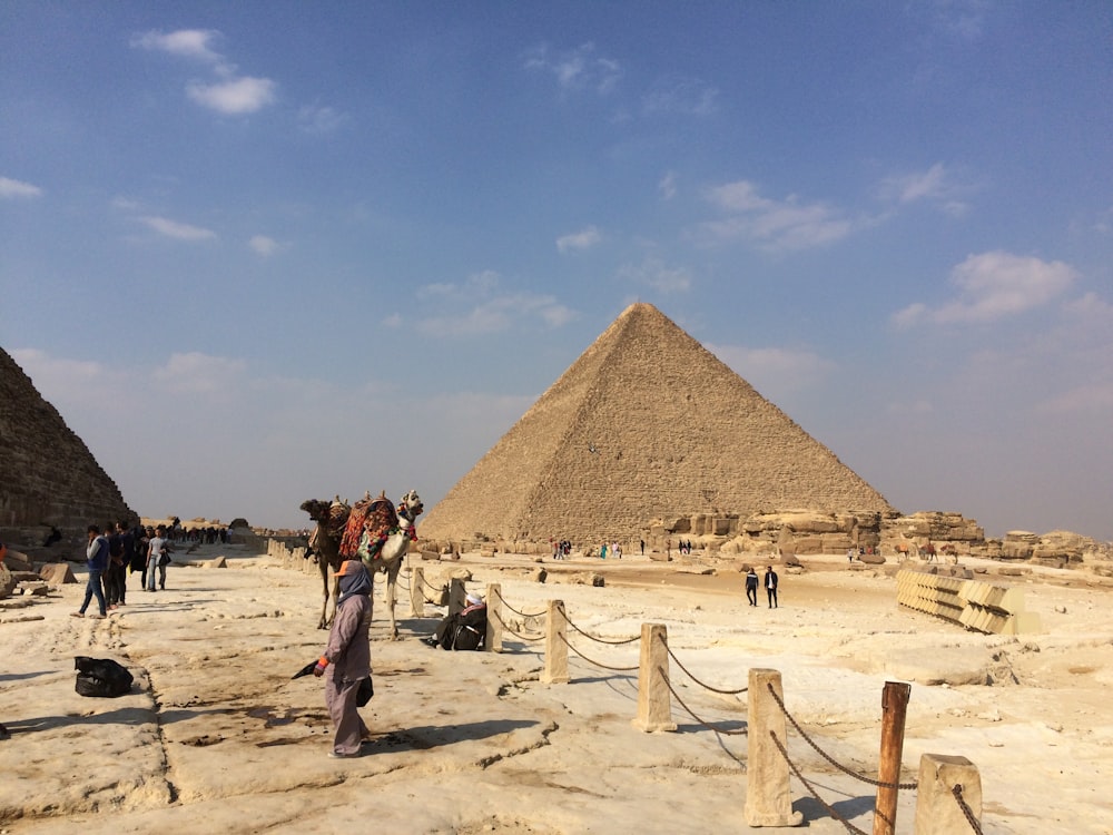 persone in piedi vicino alla Piramide di Giza sotto il cielo blu e bianco durante il giorno