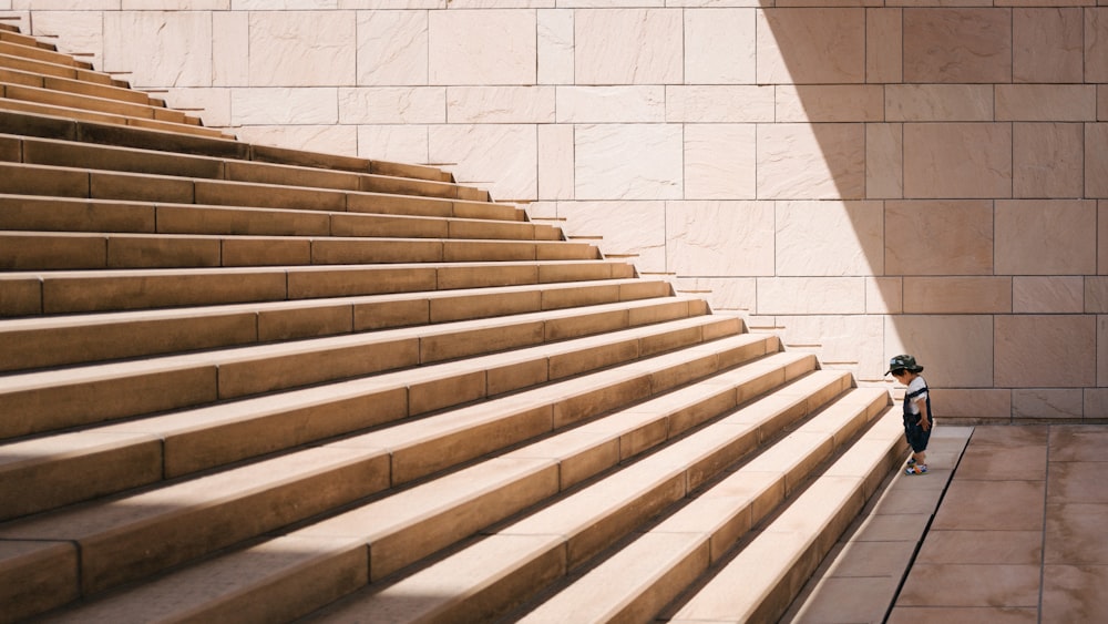 Kleinkind steht vor beigefarbener Betontreppe