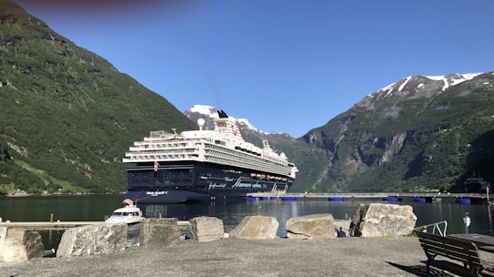 A serene cruise ship sailing past towering Alaska glaciers under a clear blue sky.