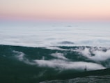 Clouds forming shapes over a peaceful valley at dusk.