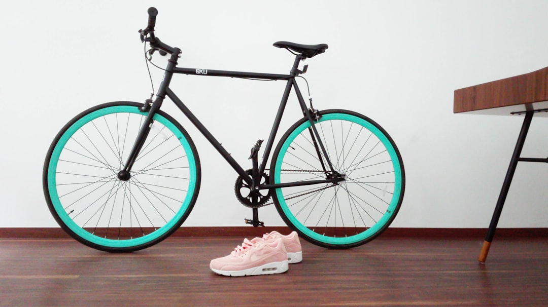 black and green road bike near pair of pink-and-white Nike Air Max Command