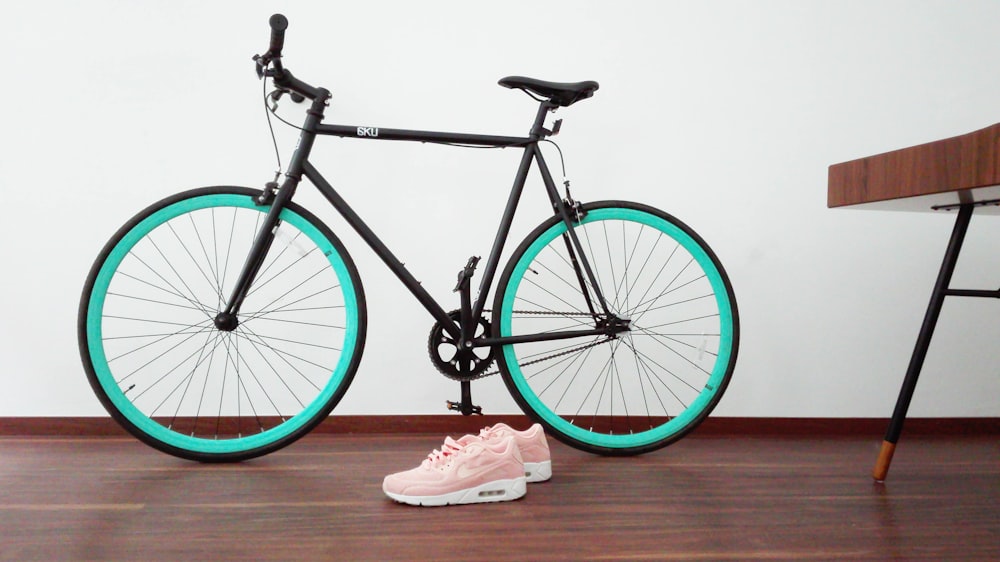 vélo de route noir et vert près de la paire de Nike Air Max Command rose et blanc