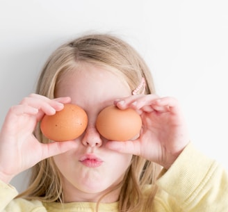 girl holding two eggs while putting it on her eyes