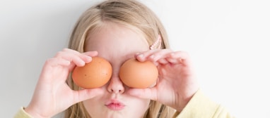 girl holding two eggs while putting it on her eyes