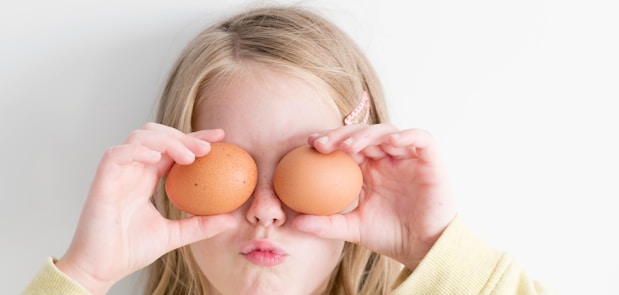 girl holding two eggs while putting it on her eyes
