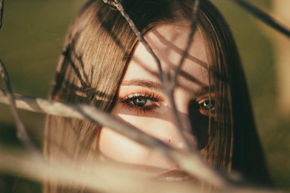 woman standing behind bare tree branch