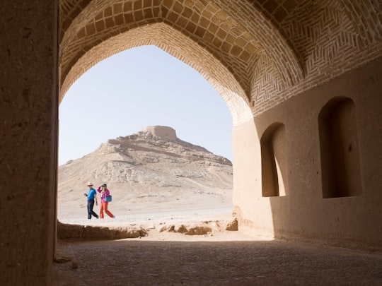 2 person standing beside brown building in دخمه زرتشتیان Iran