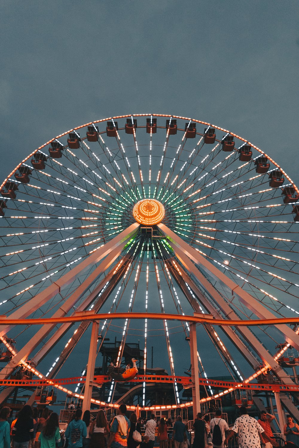 people in front of ferris wheel under gray sky