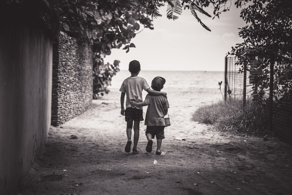 Photographie en niveaux de gris d’un enfant et d’un tout-petit en marchant