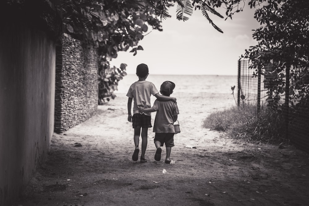 fotografia in scala di grigi di bambino e bambino mentre cammina