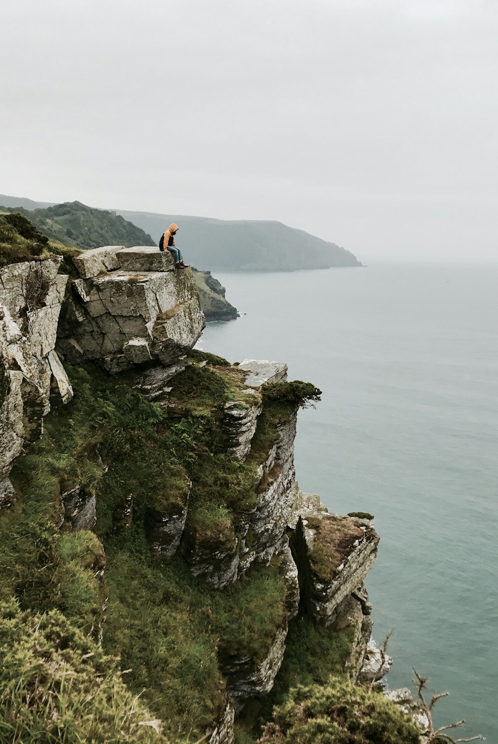 personne assise à flanc de falaise pendant la journée