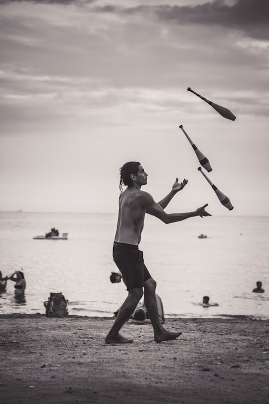 grayscale photo of man juggling on shore in Taganga Colombia