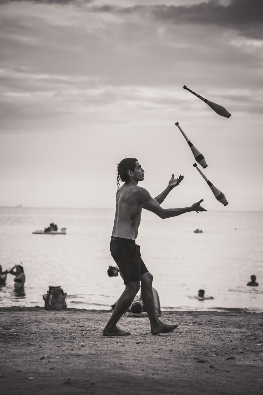 grayscale photo of man juggling on shore