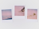 Three Polaroid-style photographs depict minimalistic coastal scenes with soft, faded colors. The left image shows a calm sea with subtle waves, the middle image presents a rocky coastline with a cliff, and the right image includes a sandy beach with a large rock formation.