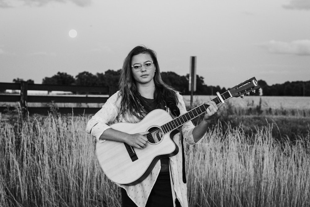 woman standing while playing guitar