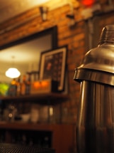 A sleek black and gold cocktail shaker with a stylish bar backdrop.