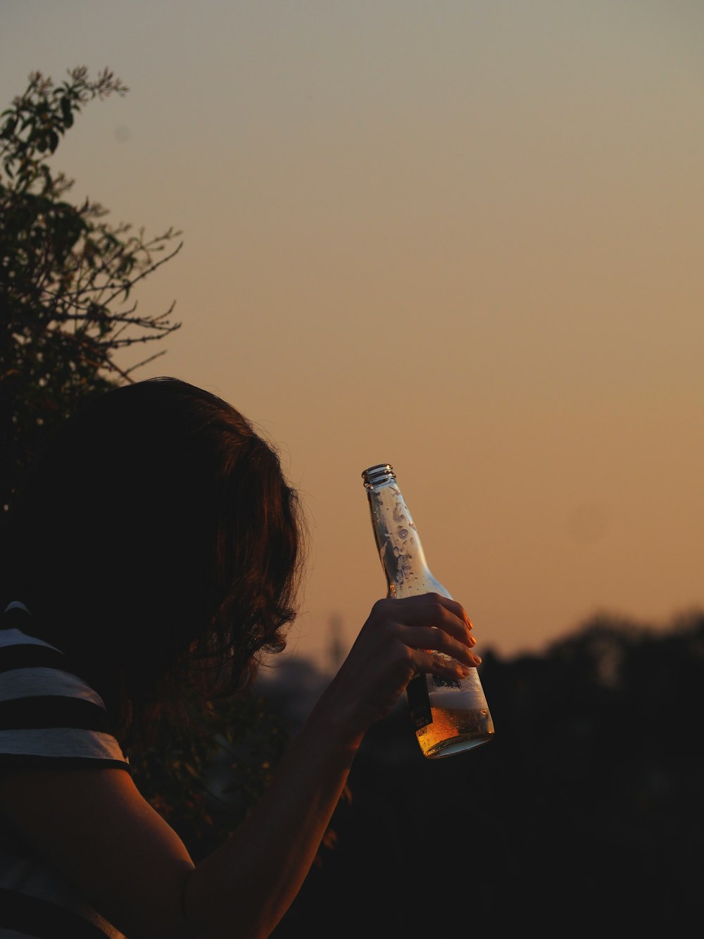 woman holding bottle near bush