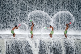 four men throwing dipper of water on waterfalls during daytime