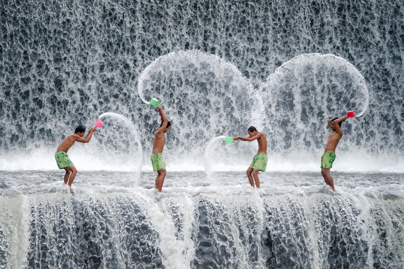 four men throwing dipper of water on waterfalls during daytime