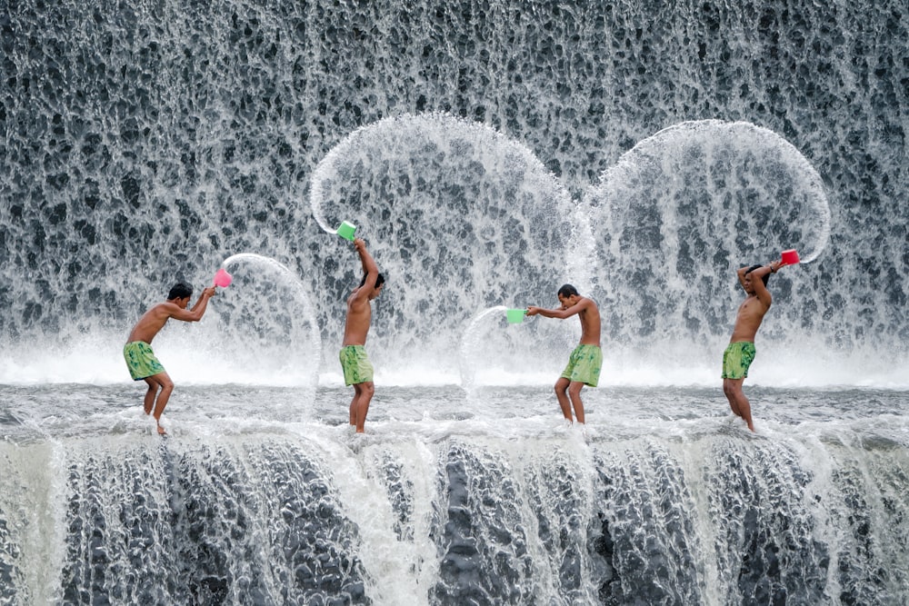 Cuatro hombres lanzando un cucharón de agua en cascadas durante el día